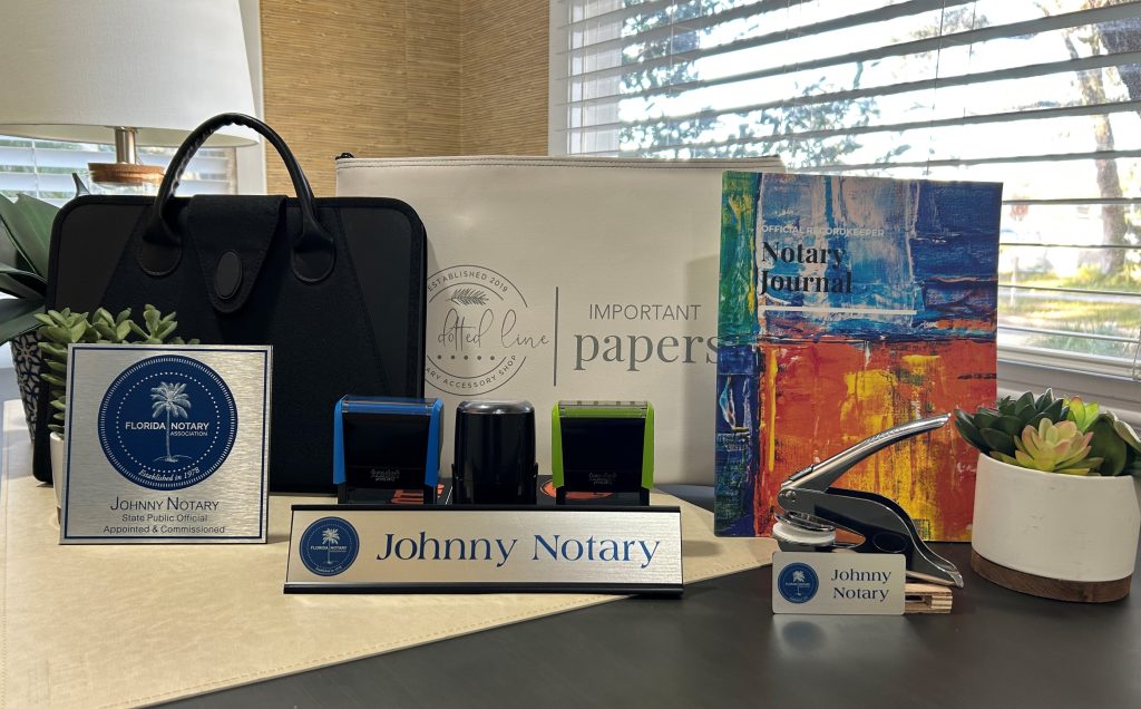 Desk with Notary Public Record Book, Florida Notary Reference Manual, notary stamp, Florida Notary Association briefcases, and a name tag with the name "Johnny Notary"